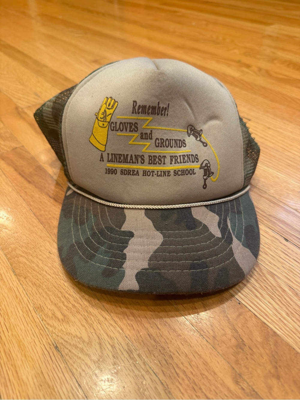 Remember Gloves and Grounds Lineman 1990 Camo Trucker Hat with Yellow Graphic